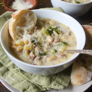 A white bowl of creamy potato soup with sausage.