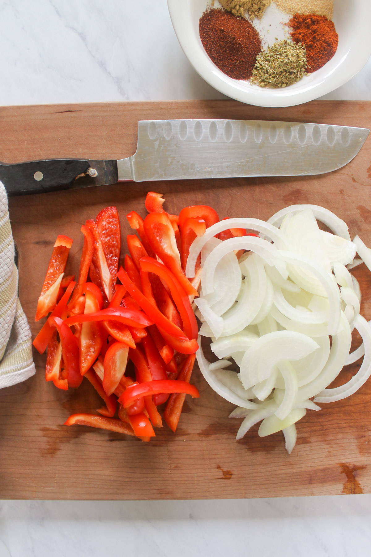 A cutting board with sliced red bell peppers and onions.