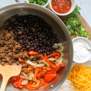 A skillet with ground beef, black beans, peppers and onions.