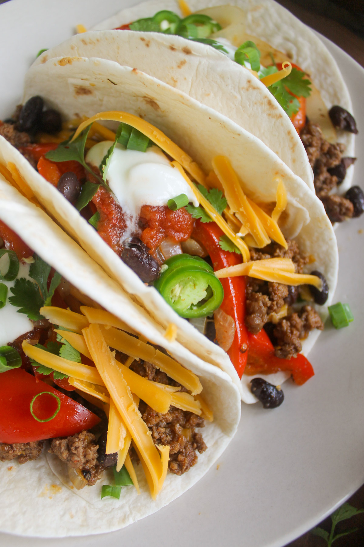 Soft shell tacos with ground beef, peppers, onions, black beans and cheese.