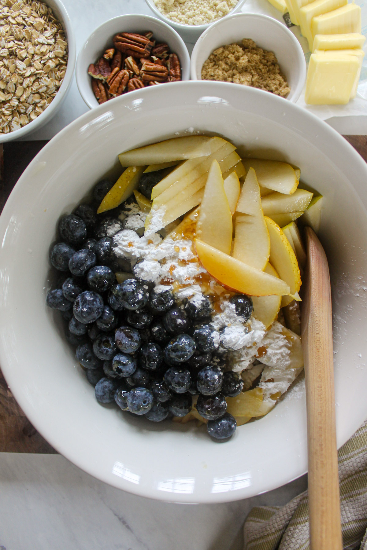 A bowl of filling for a pear crisp with fresh blueberries.