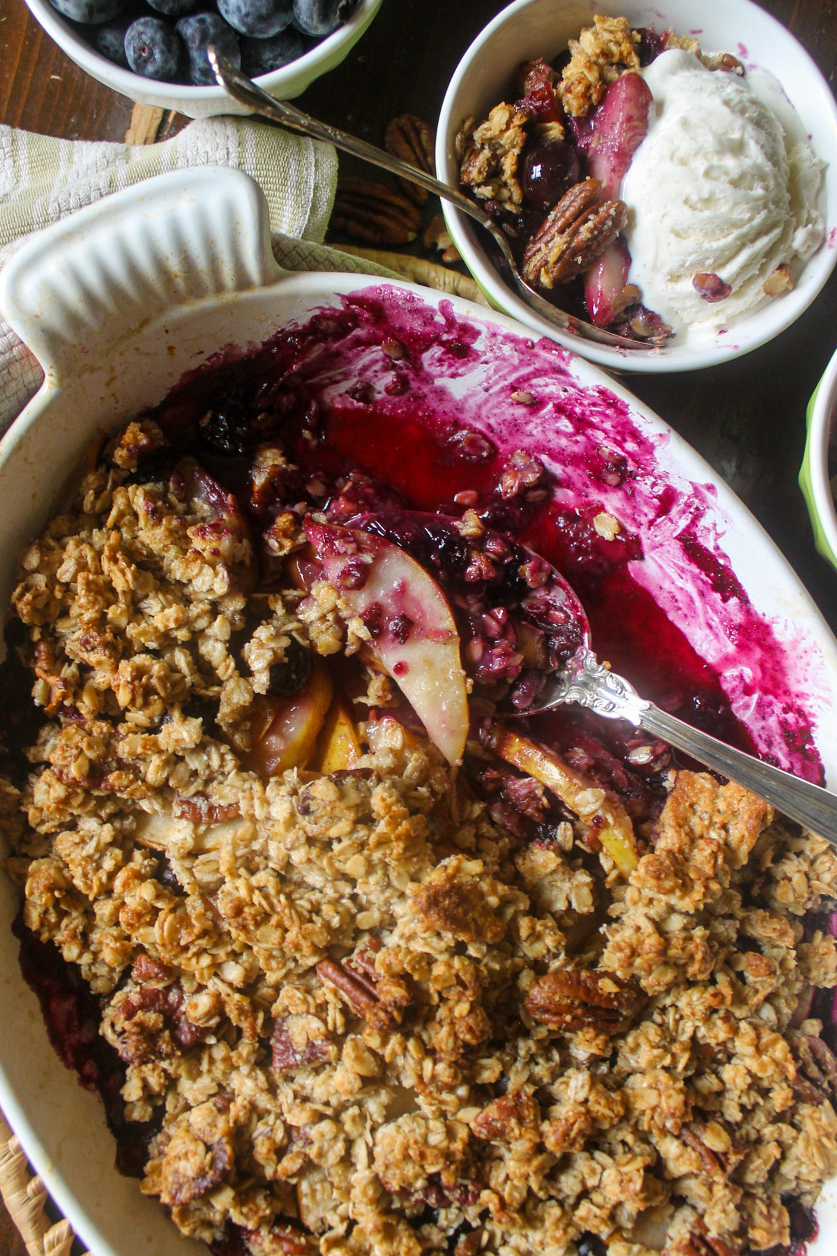 Purple fruit filled Pear Blueberry Crisp with bowls served with ice cream.