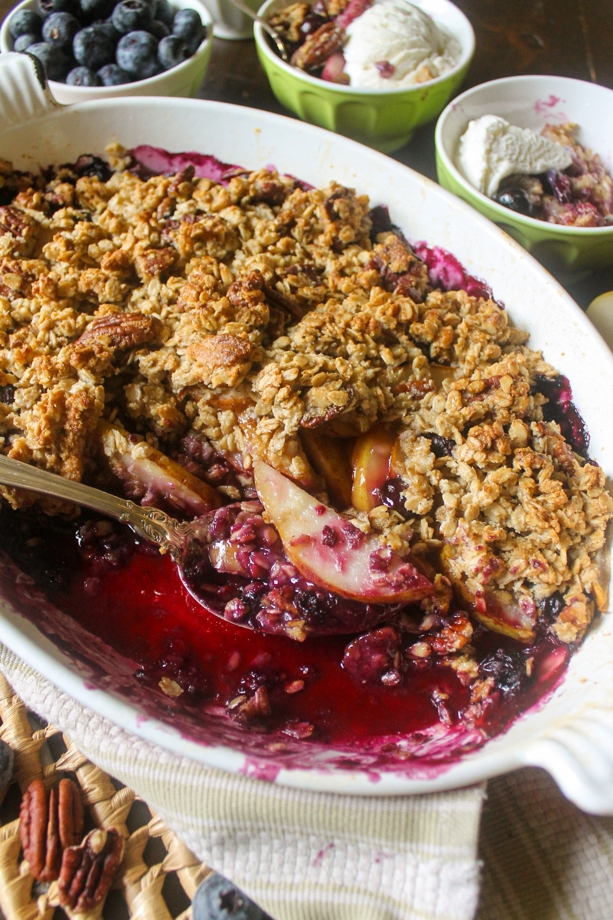 An oval baking dish of Pear Blueberry Crisp with oat pecan topping.