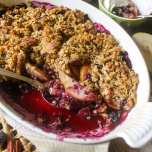 A dish of blueberry pear crisp with a spoon.