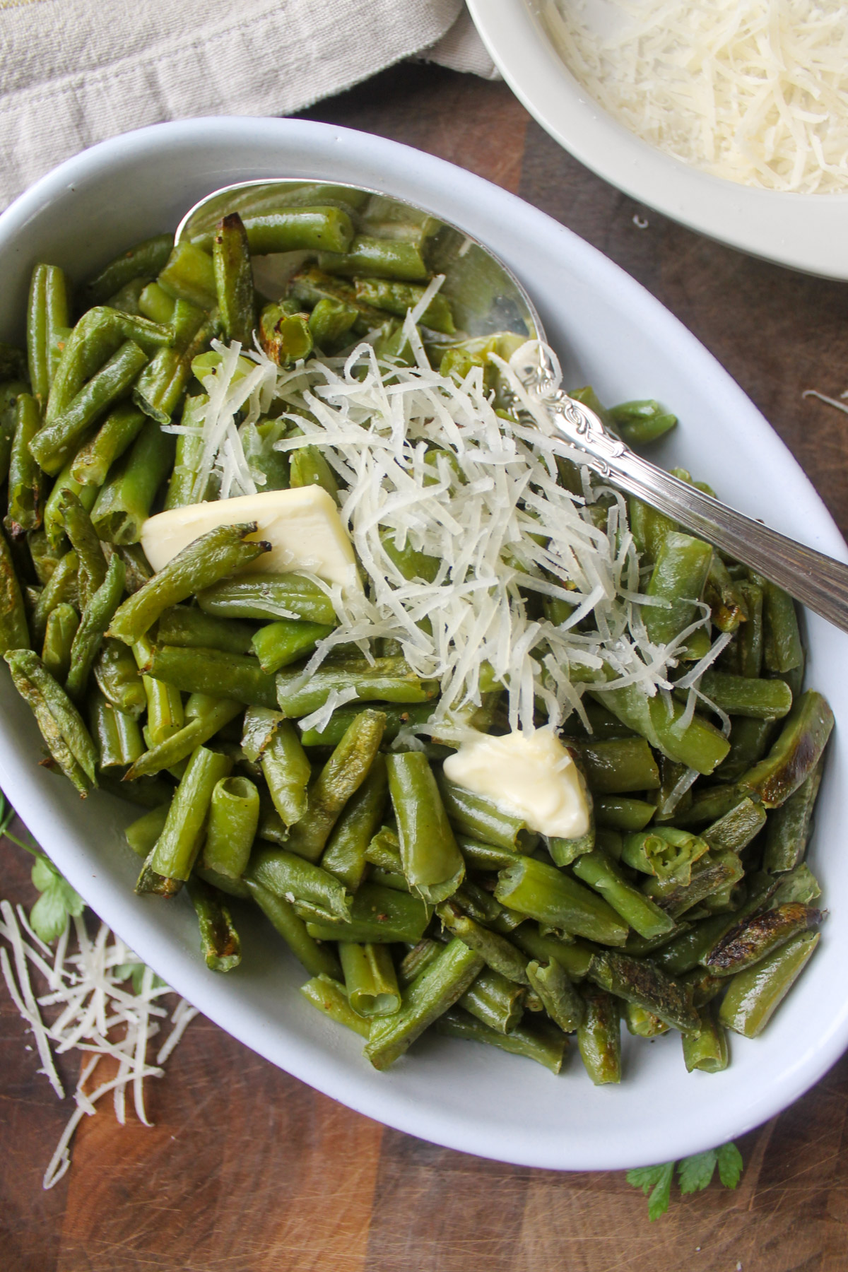 A dish of roasted frozen green beans topped with butter and cheese.