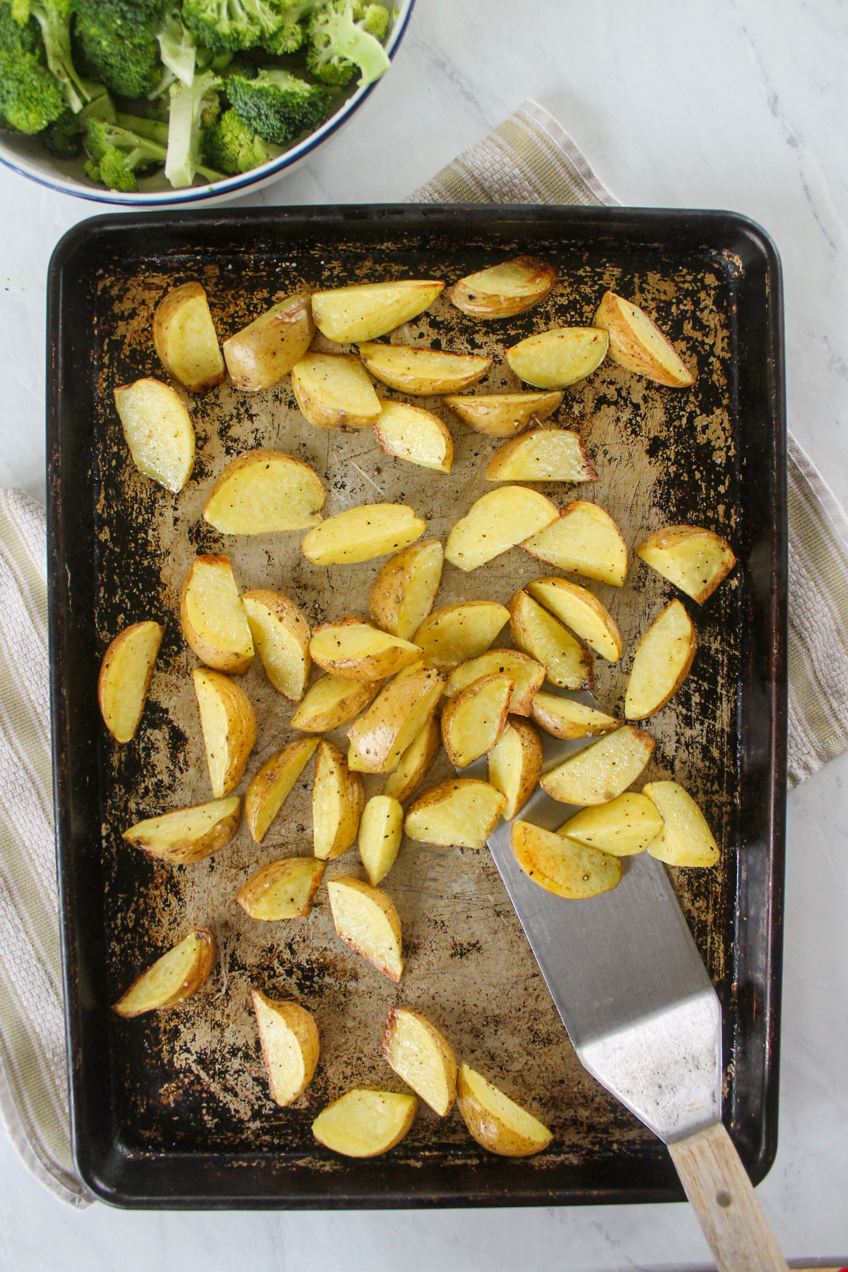 Roasted potatoes on a sheet pan with a spatula.