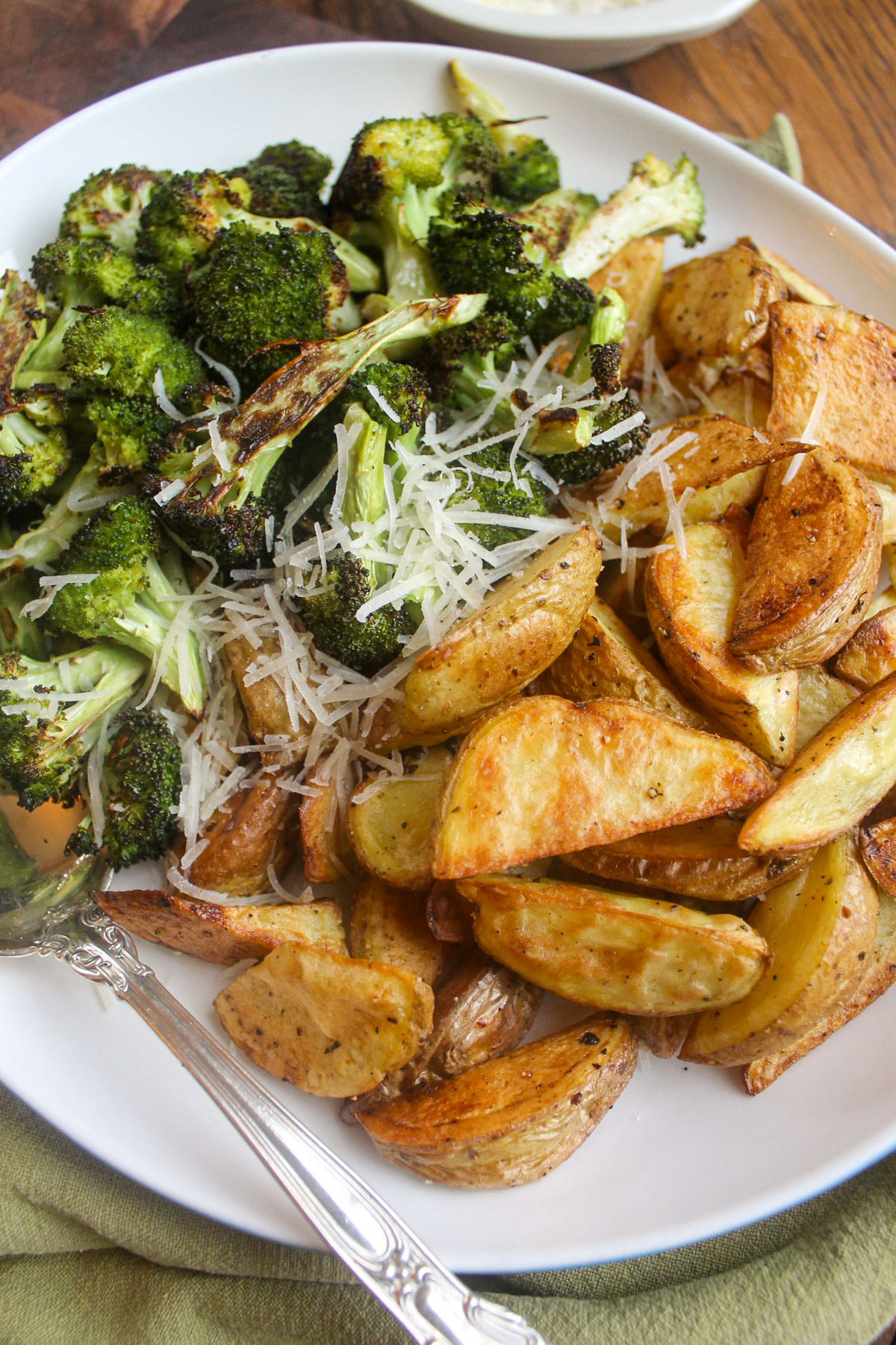 Roasted potatoes and broccoli with Parmesan cheese on a platter.