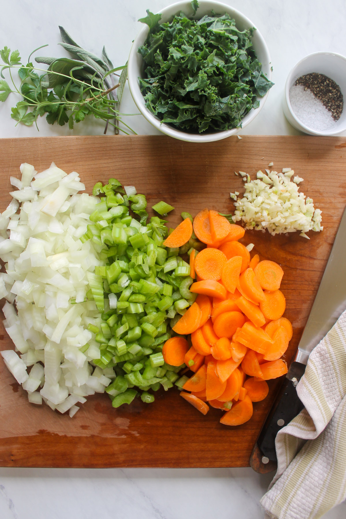 Chopped onions, celery, carrots and garlic on a cutting board.