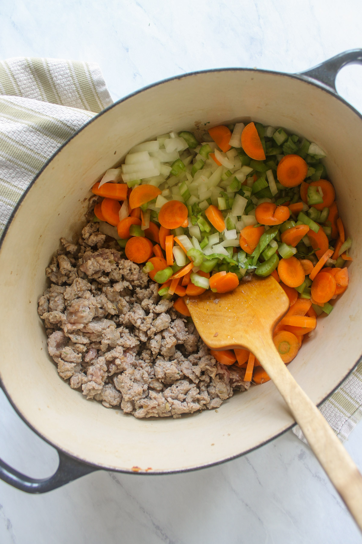 A pot with cooking sausage and vegetables.