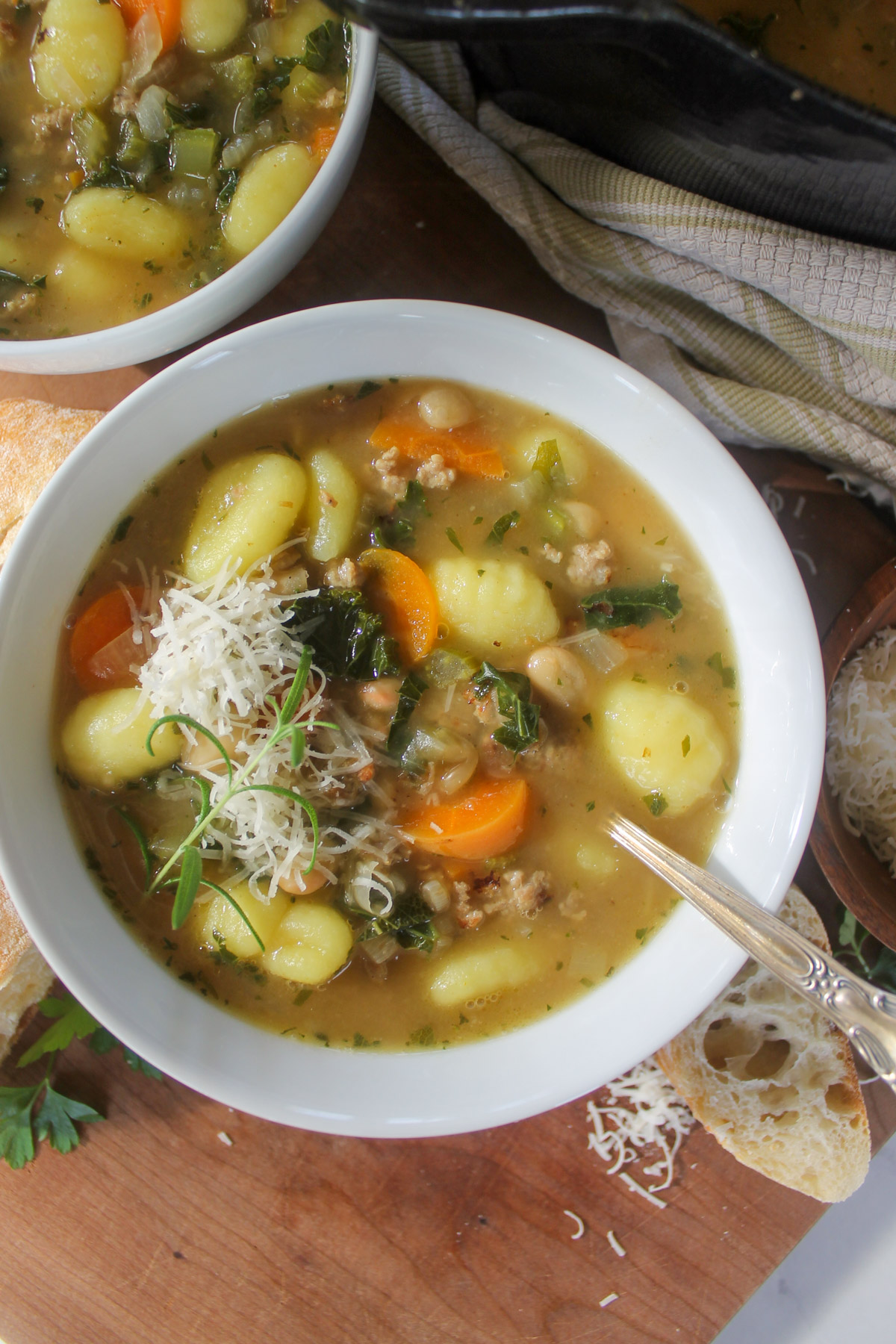 A bowl of sausage gnocchi soup with Parmesan cheese.