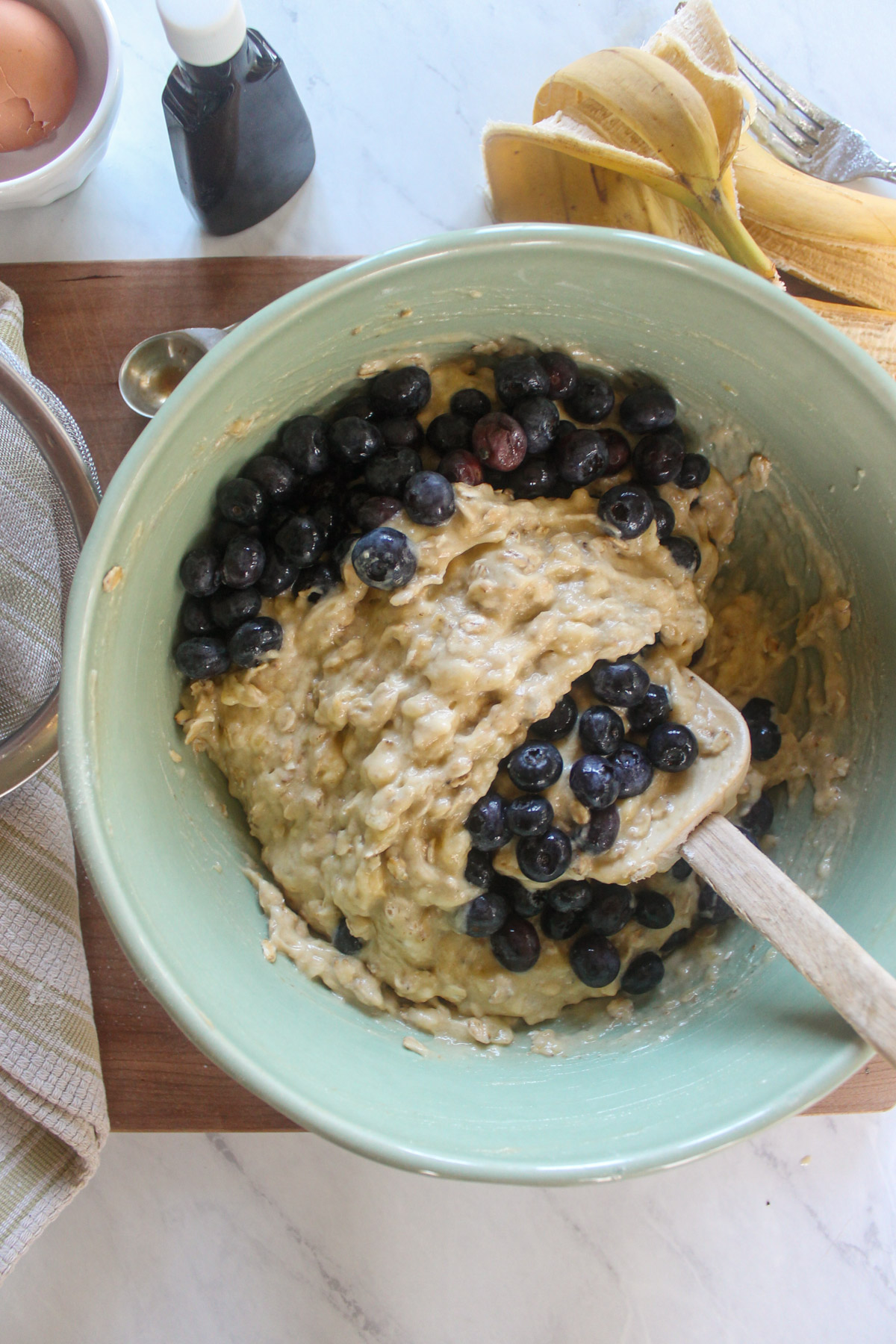 Folding fresh blueberries into muffin batter.