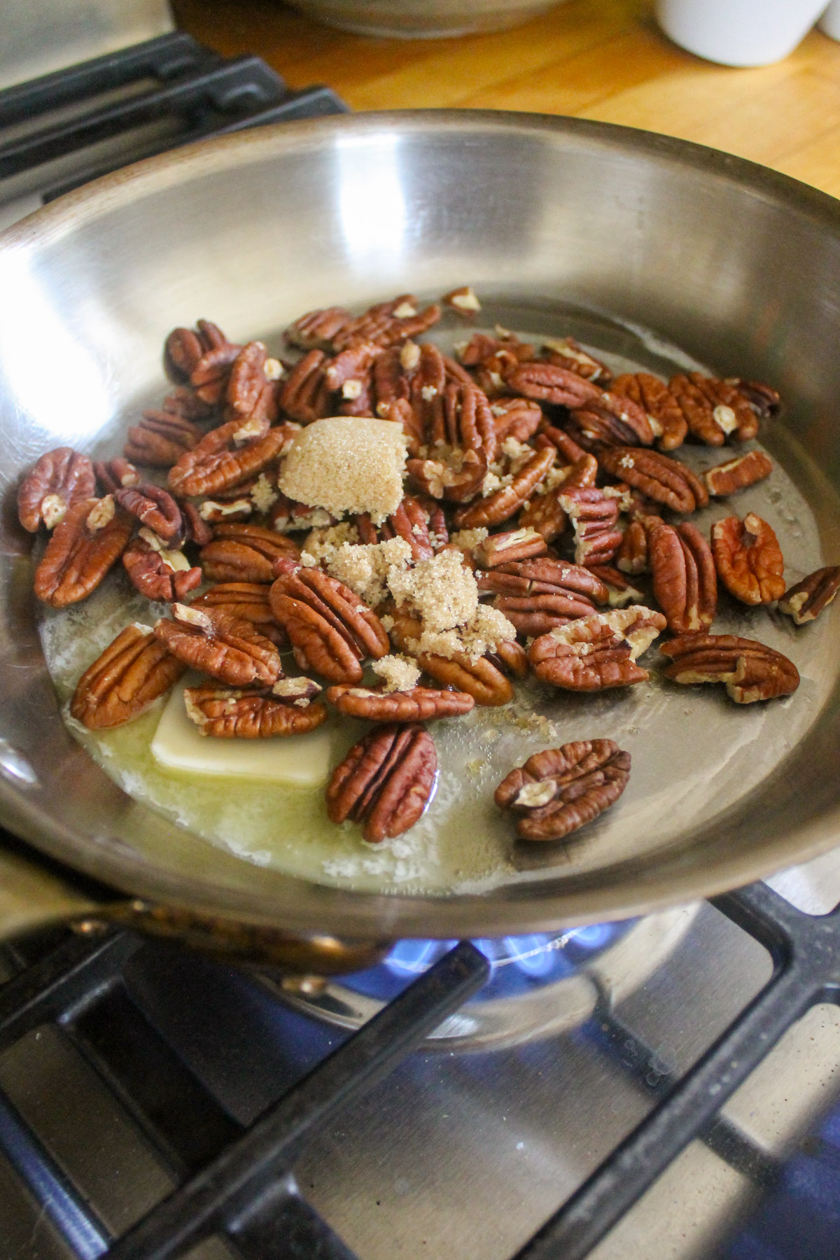 Toasting pecans in a skillet with butter and brown sugar.