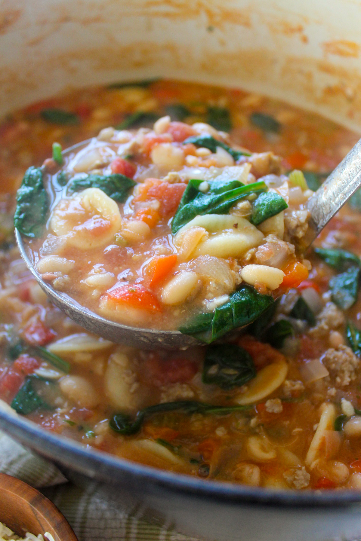 A ladle full of White Bean Pasta Soup with Sausage.