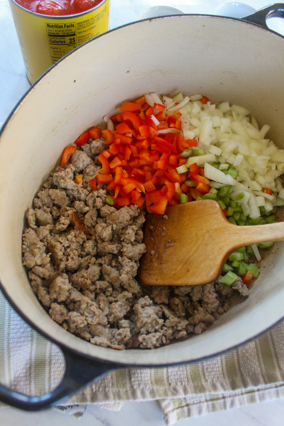 Sausage browning in a soup pot with onion, red bell pepper and celery.