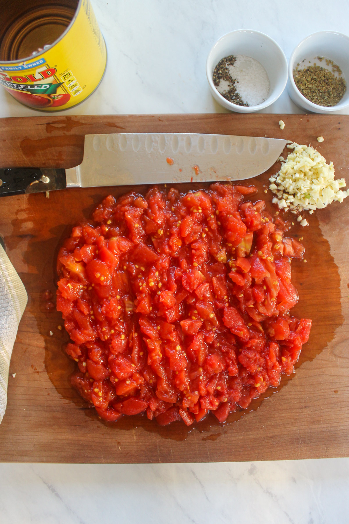 Chopping canned tomatoes on a cutting board.