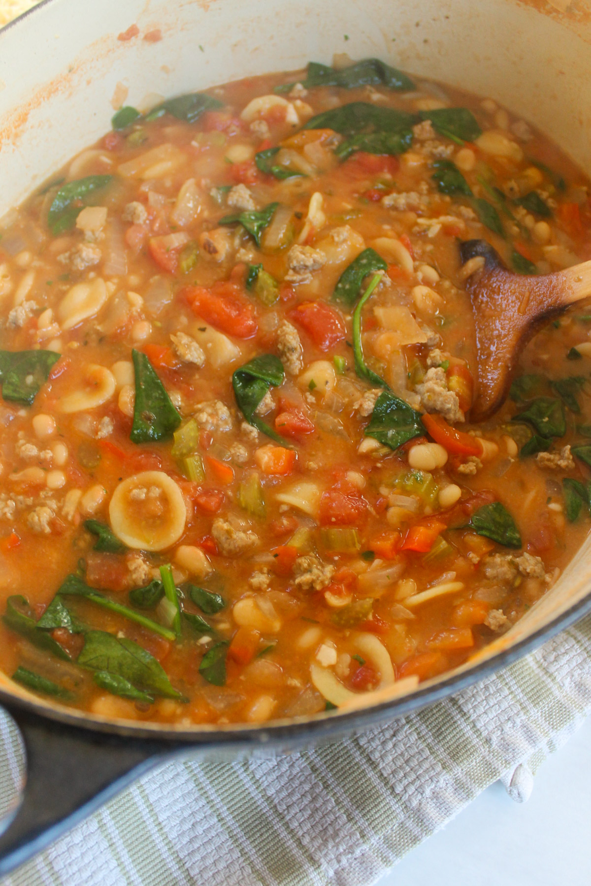 A pot of Italian sausage white bean soup with pasta and spinach.