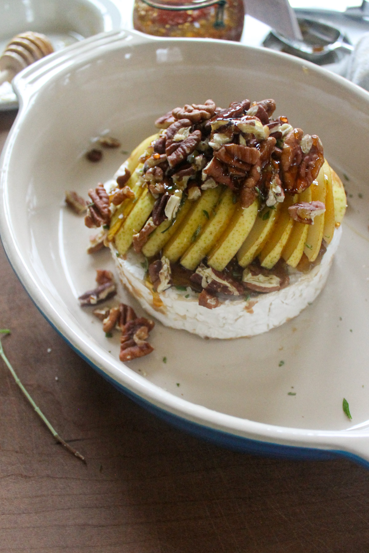 Raw sliced pears piled on brie with pecans and honey.