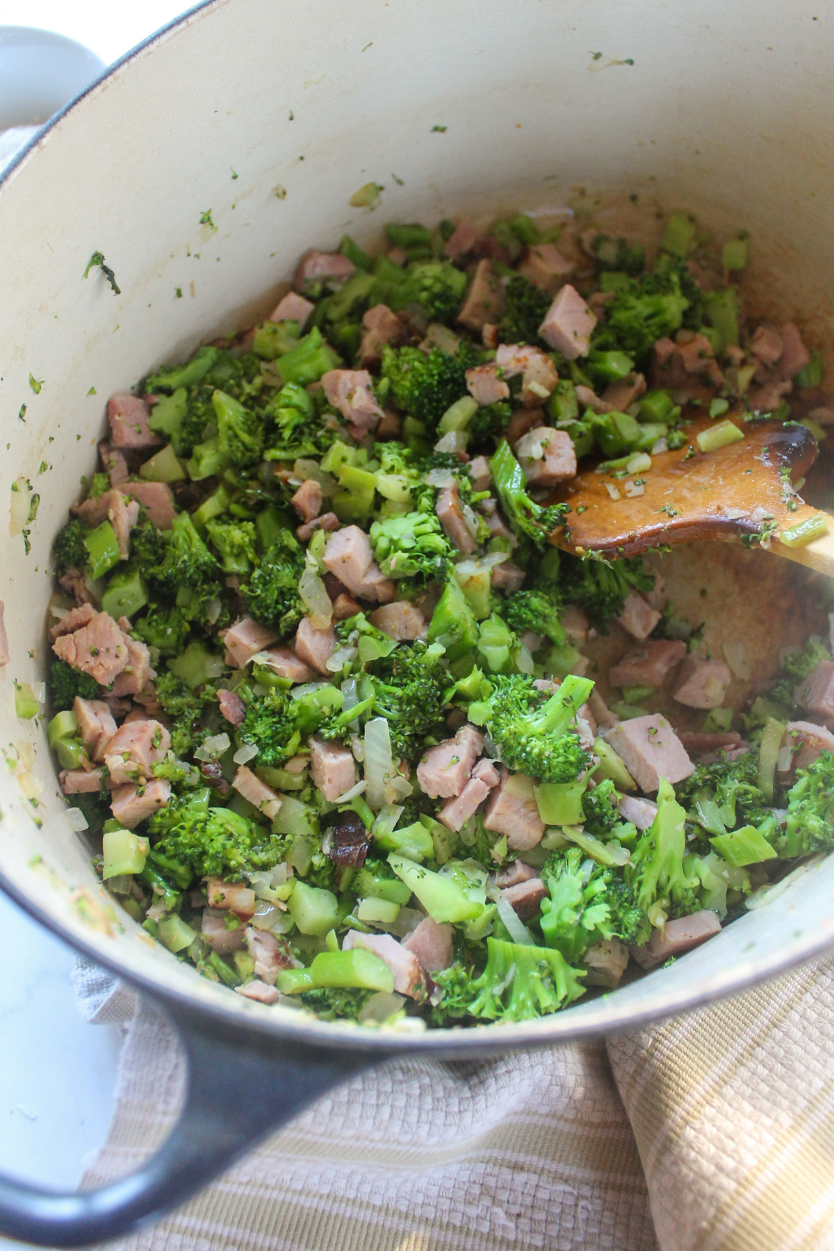 A soup pot with sautéd broccoli, onions, and chopped ham.