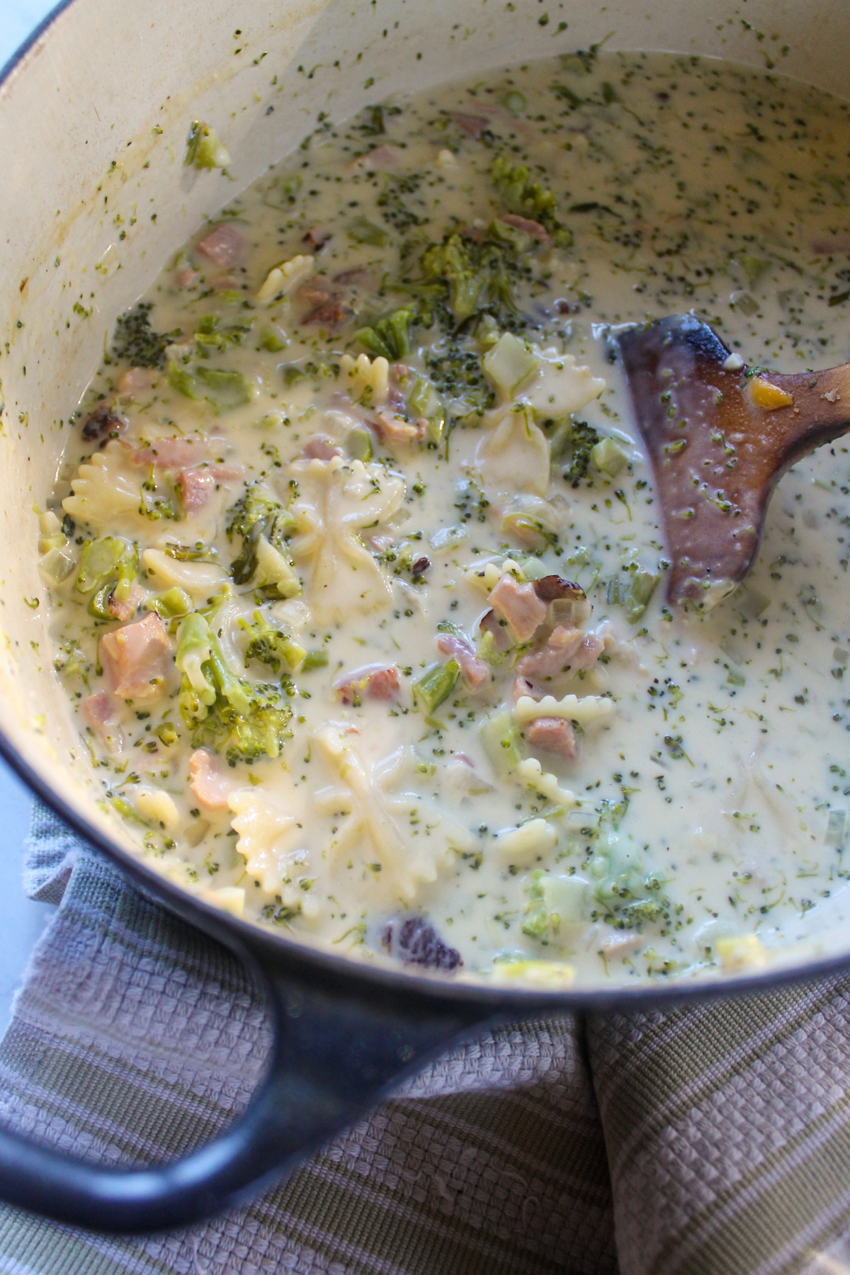 A soup pot of broccoli ham soup with cheese and farfalle pasta.