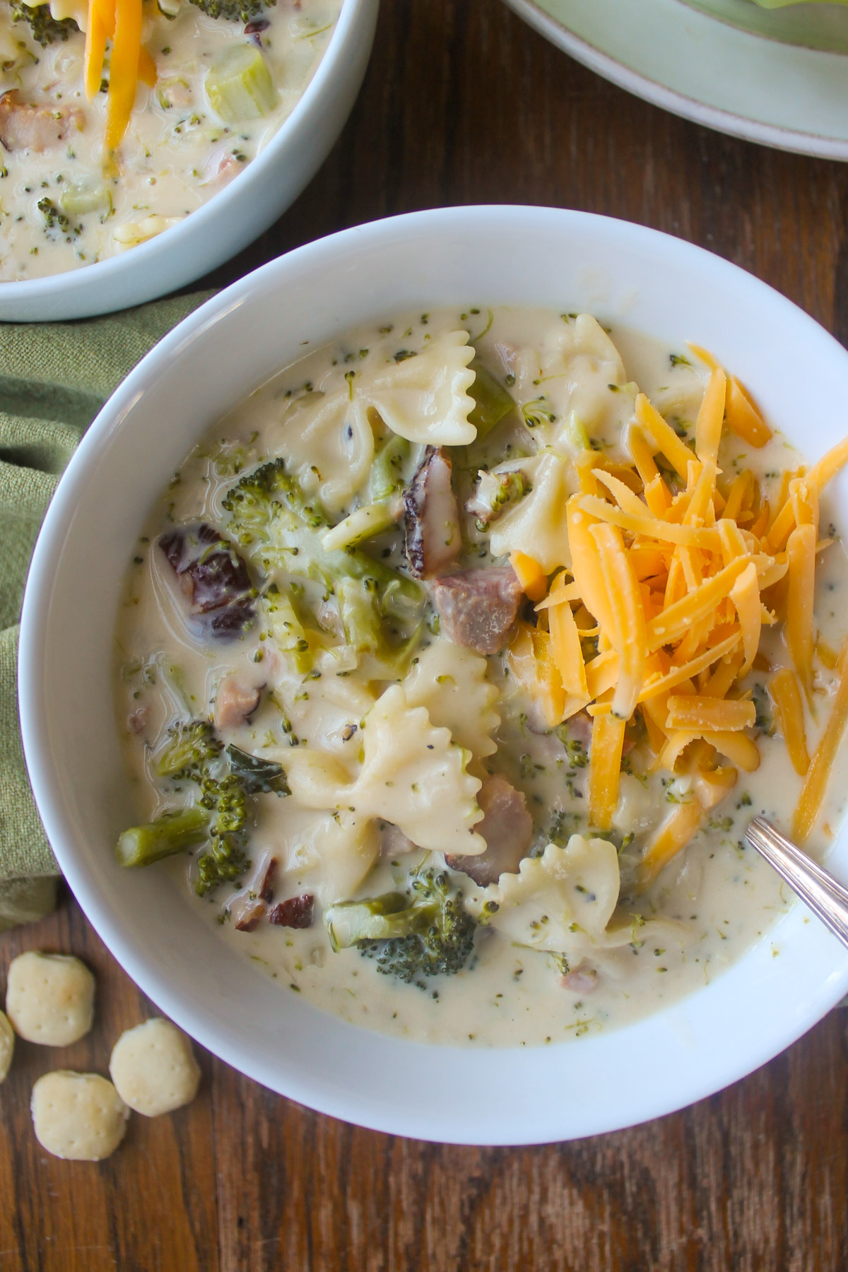 A bowl of broccoli cheese soup with ham and bowtie pasta.