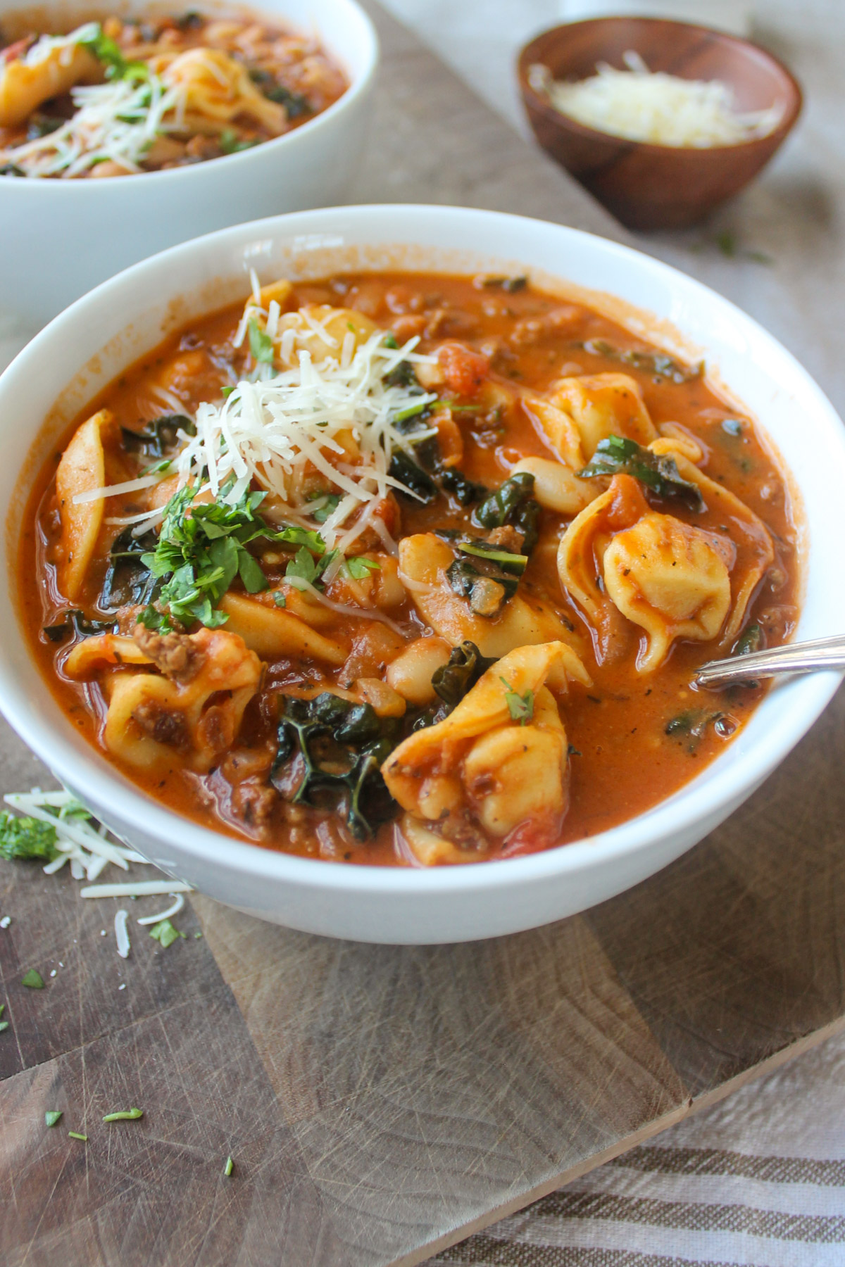 A bowl of tortellini tomato soup with kale and beef.