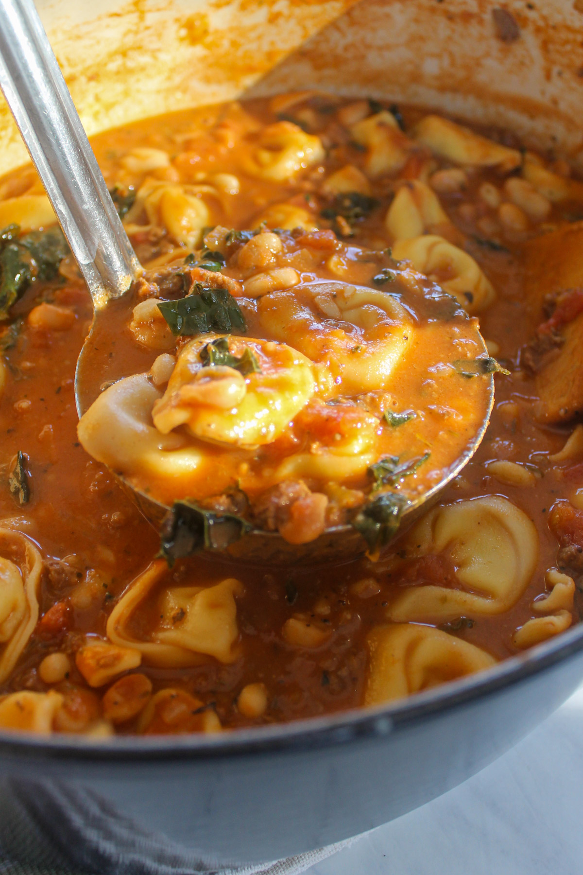 A ladle full of tortellini soup.