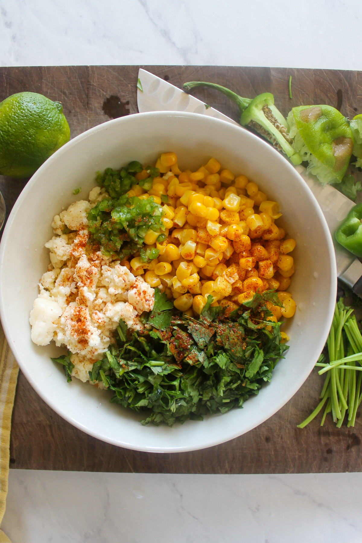 A bowl with ingredients for Cotija cheese corn salsa with cilantro.