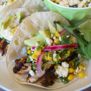 Blackened chicken tacos topped with red onions, avocado and spicy corn Cotija cheese salsa.