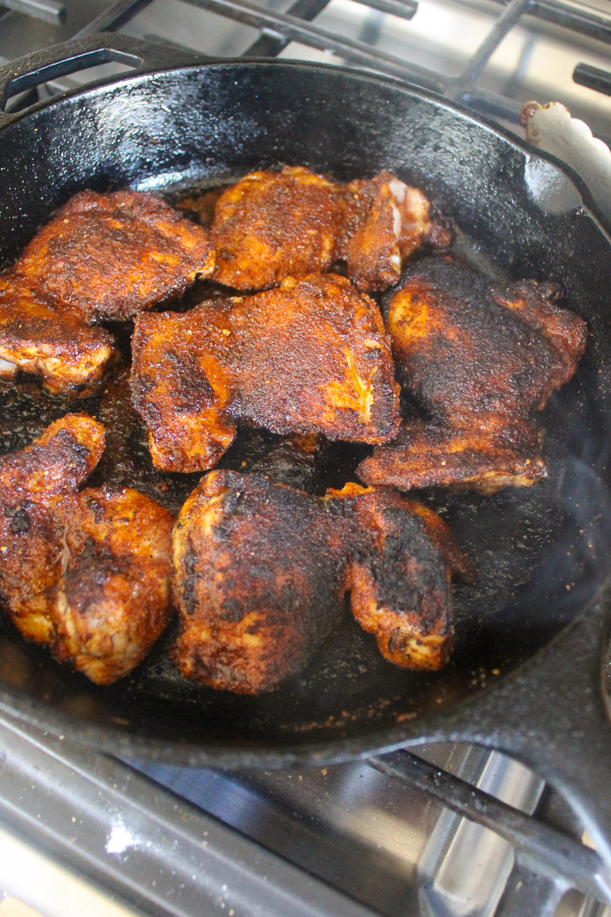 Blackened chicken thighs in a cast iron skillet.