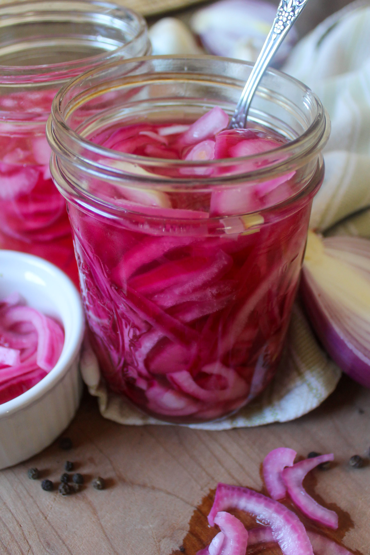 A jar of pickled red onion slices in pink colored brine.