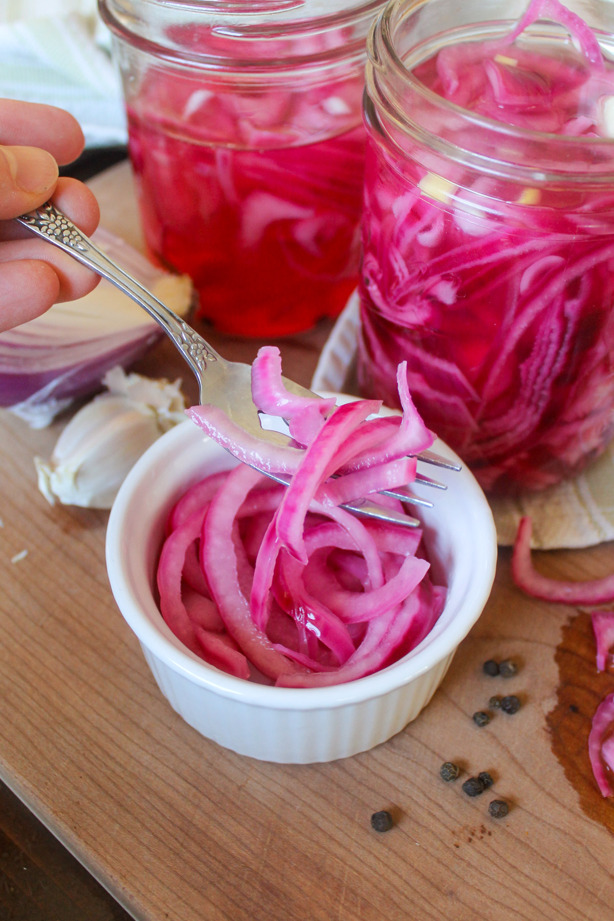 A fork dipping into a small white bowl of pickled red onions.