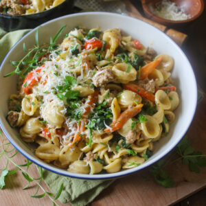 A serving bowl of orecchiette with Italian sausage and vegetables.