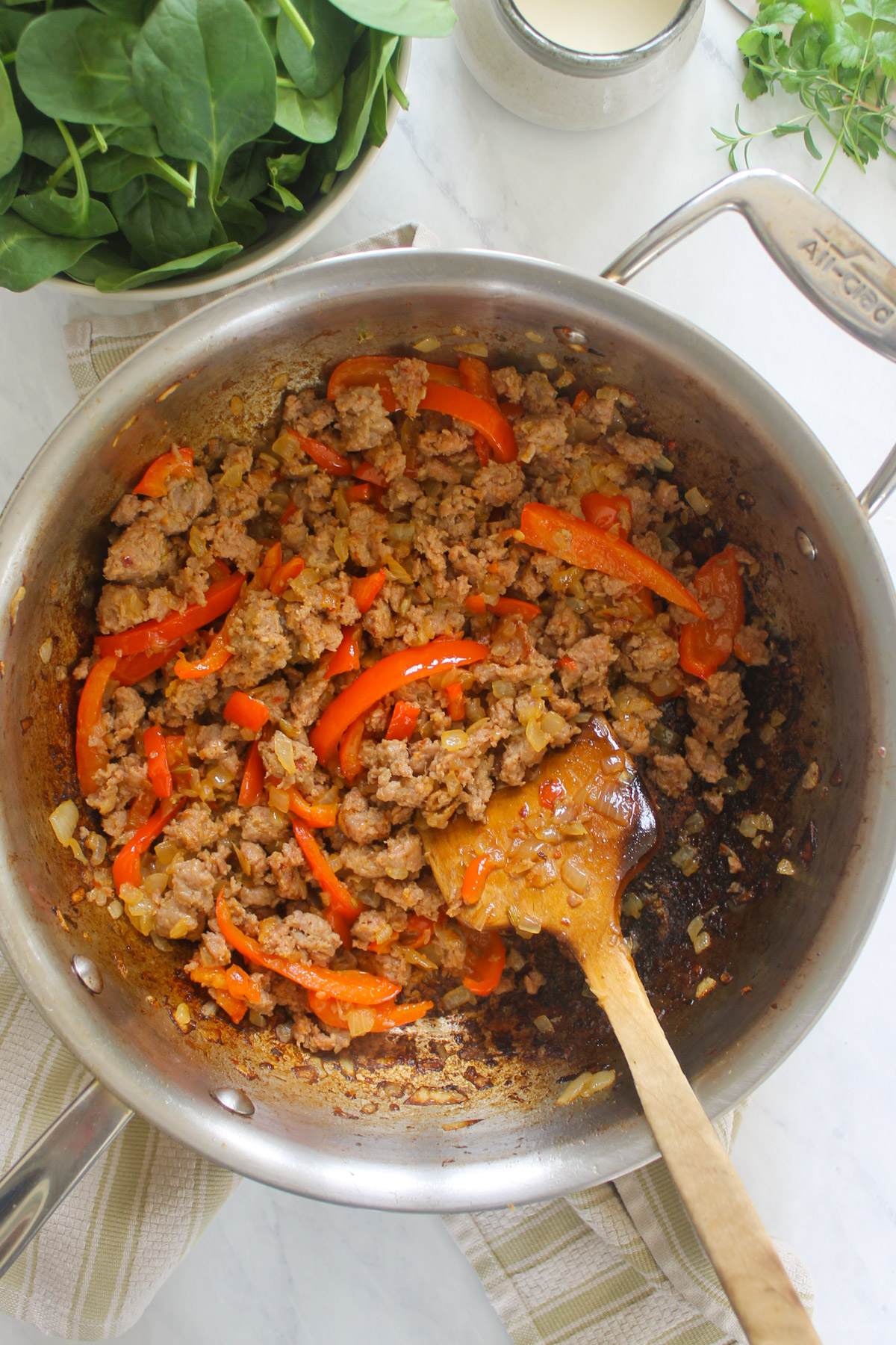 Browned sausage in a skillet with onions and peppers.