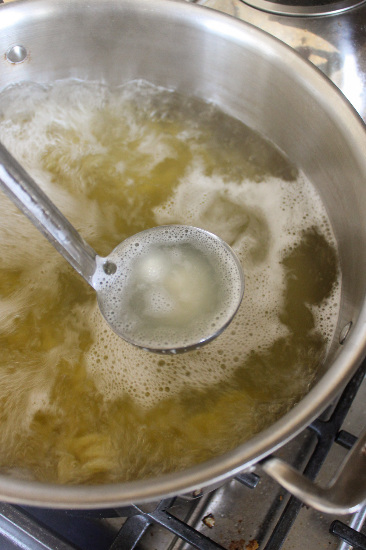 Scooping boiling pasta cooking water out with a ladel.