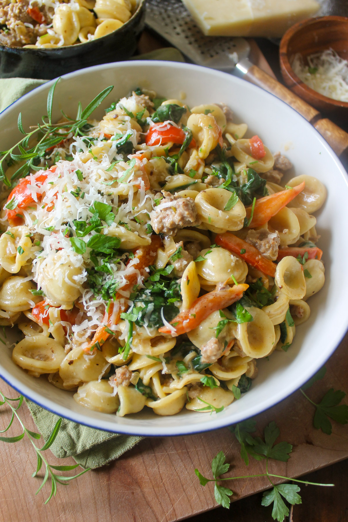 A bowl of orecchiette pasta with Italian sausage, red peppers, and herbs.