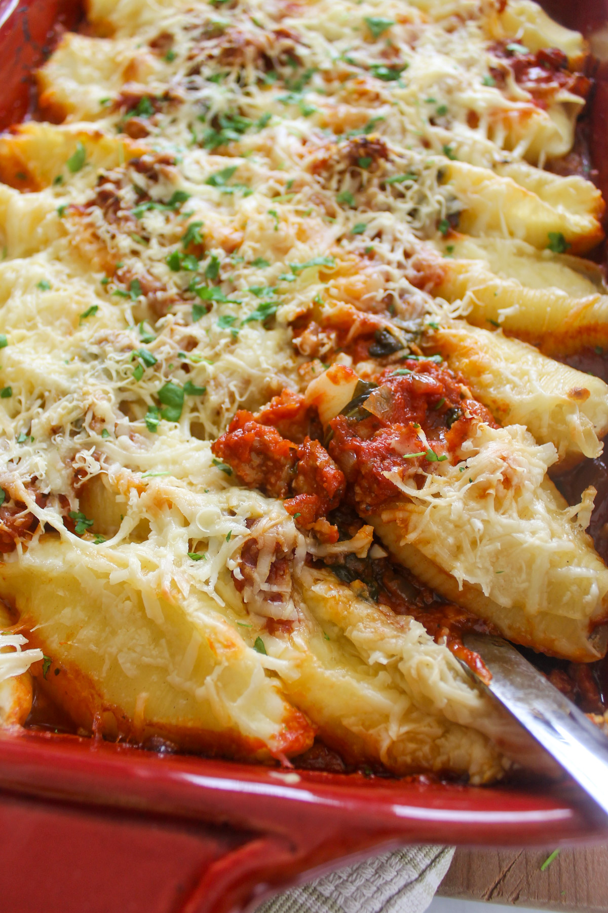 A baking dish of cheesy stuffed shells with sausage meat sauce.